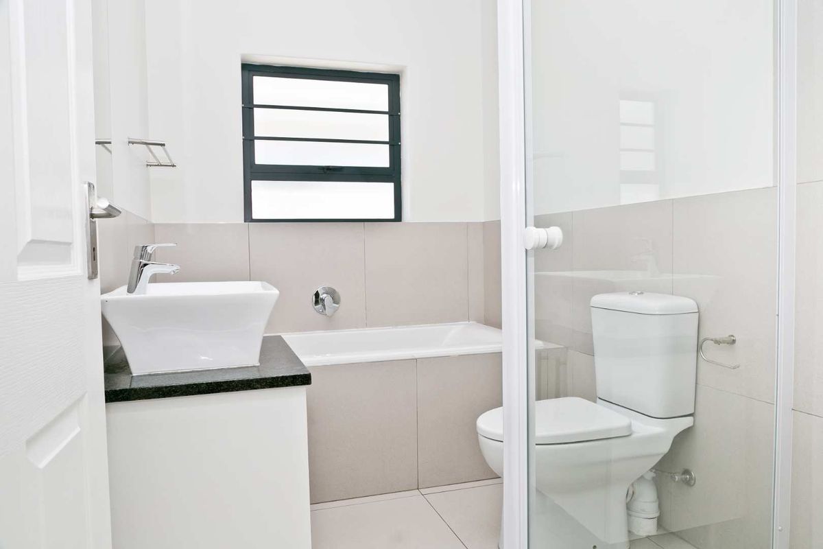 A clean, modern bathroom featuring a vessel sink on a granite vanity, a built-in bathtub, and a separate shower enclosure with neutral tiling.