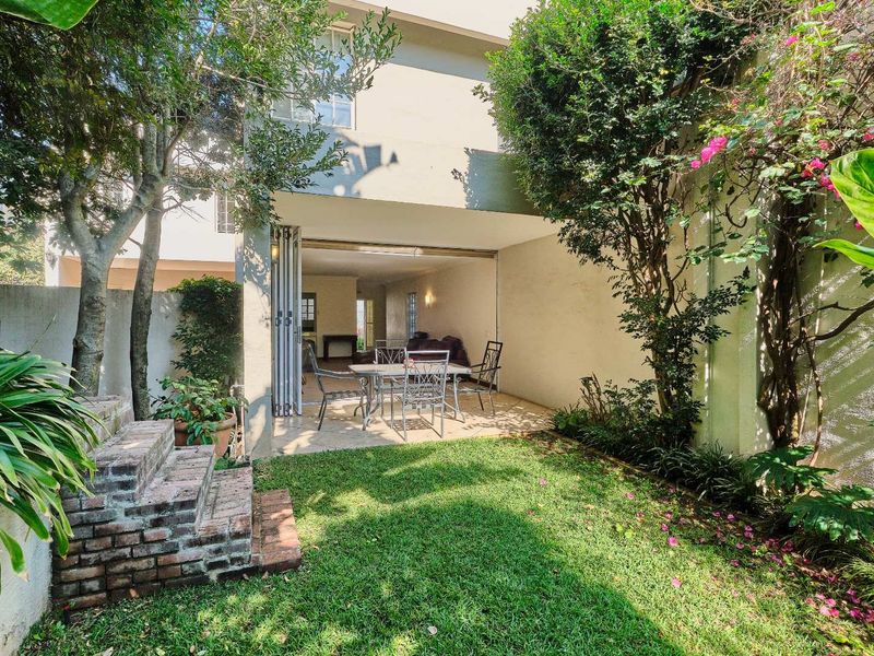 A private rear garden featuring a covered patio with folding glass doors, providing seamless indoor-outdoor flow to the townhouse living area.