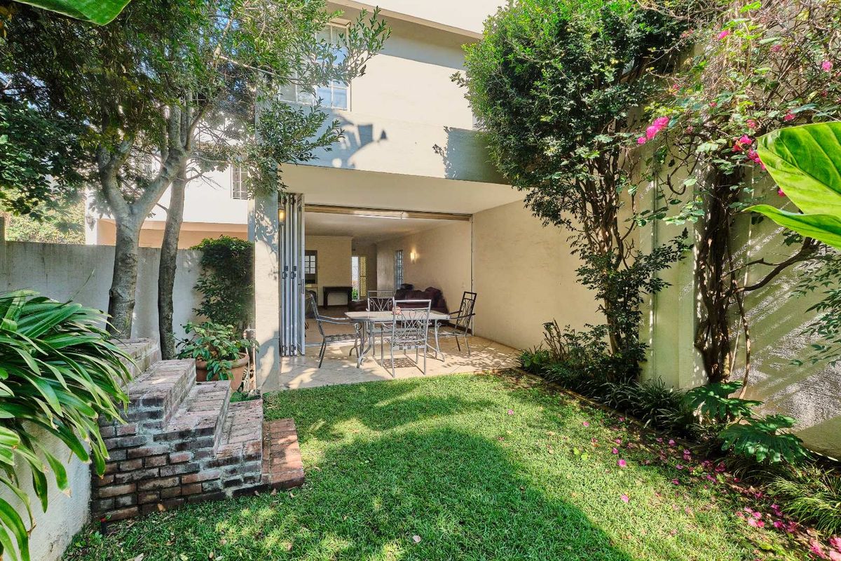A private rear garden featuring a covered patio with folding glass doors, providing seamless indoor-outdoor flow to the townhouse living area.