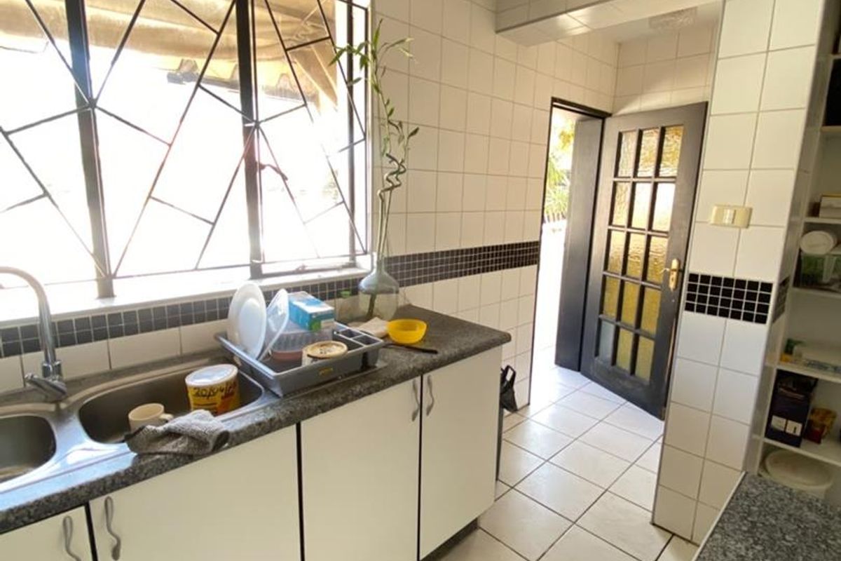 Functional kitchen featuring granite countertops, double bowl sink, tiled splashback, and recessed lighting, with direct access to an exterior doorway.