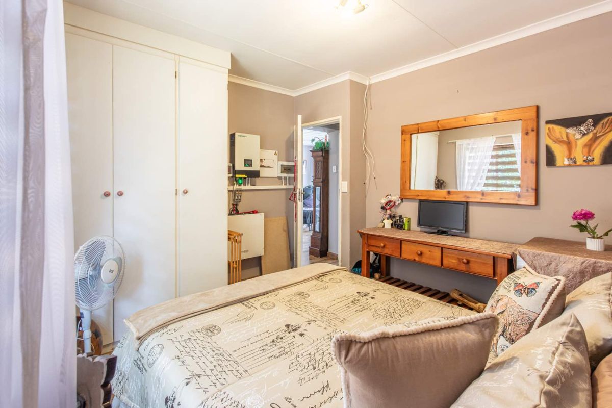 A bedroom featuring built-in wardrobes and an integrated solar inverter system mounted on the wall.
