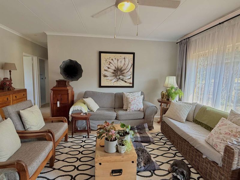 A comfortable living room featuring a ceiling fan and large windows that provide ample natural light.