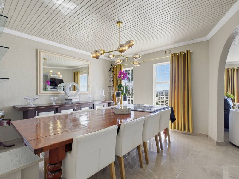 A well-maintained dining room featuring a distinctive tongue and groove ceiling, tiled flooring, and an elegant archway leading to adjacent living spaces.