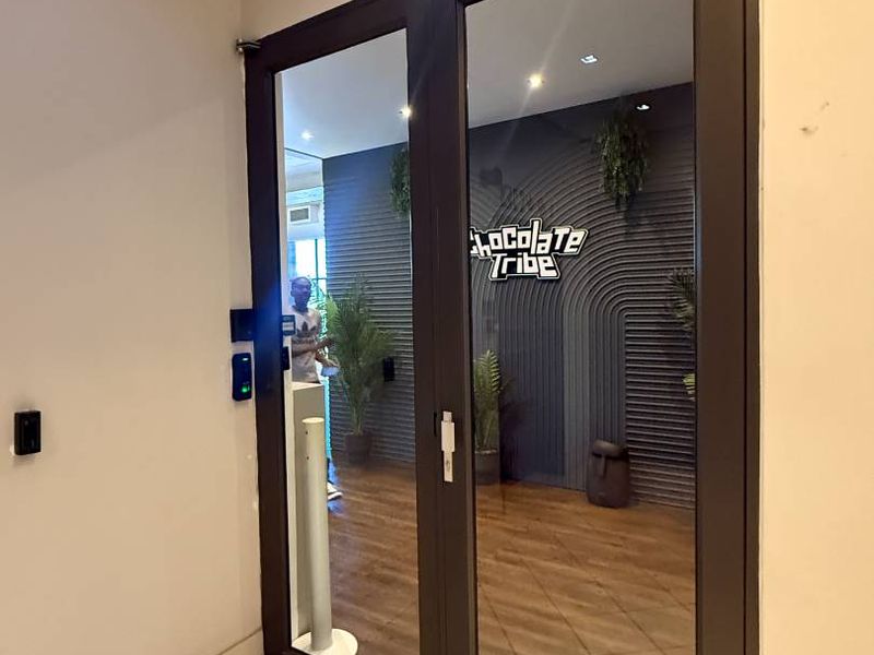 Modern retail entrance featuring glass double doors with overhead closers, recessed lighting, and clean tiled flooring leading into the main commercial space.