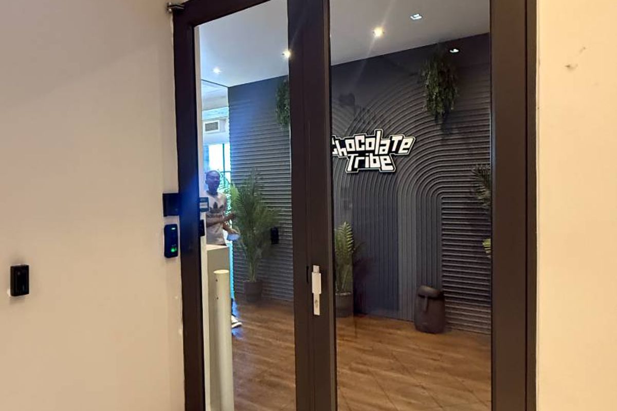 Modern retail entrance featuring glass double doors with overhead closers, recessed lighting, and clean tiled flooring leading into the main commercial space.