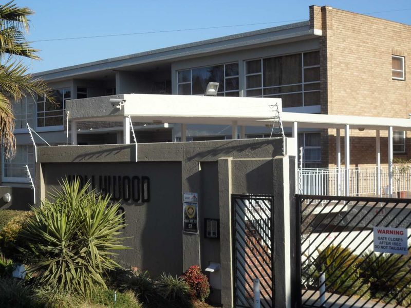 Front exterior view of the apartment complex featuring brick facade, secure gated entrance, and perimeter electric fencing.