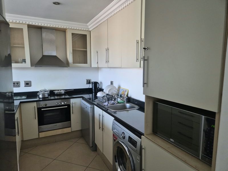 A functional kitchen featuring built-in cabinetry, granite countertops, a stainless steel oven, extractor fan, and integrated microwave with tiled flooring.