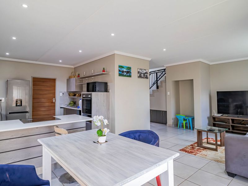 Spacious open-plan living area featuring a modern kitchen with island, built-in oven, and tiled flooring, seamlessly flowing into the lounge and dining space.
