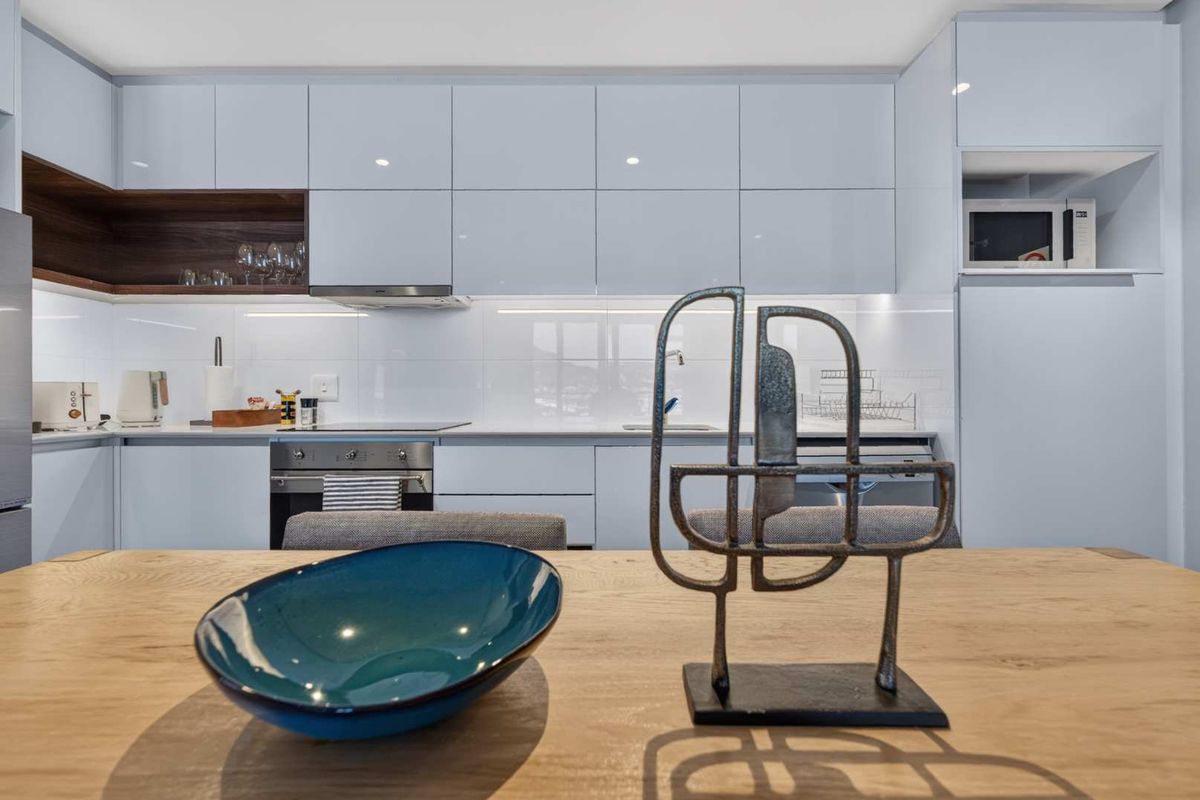 Modern kitchen featuring high-gloss cabinetry, integrated appliances, built-in oven and hob, and sleek finishes, providing a clean and functional culinary space.