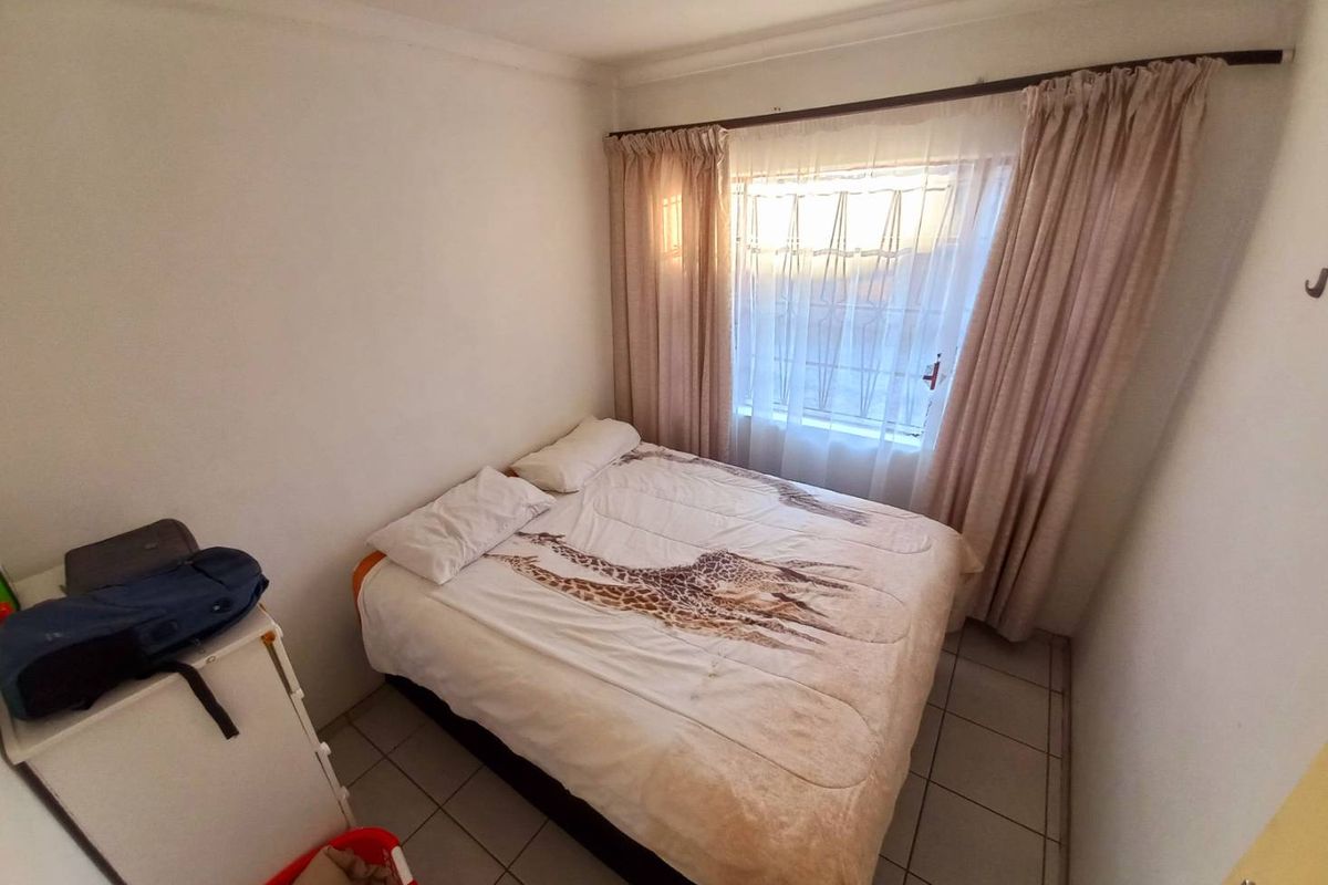 A compact bedroom featuring tiled flooring, a window with curtain rails, and neutral wall finishes.