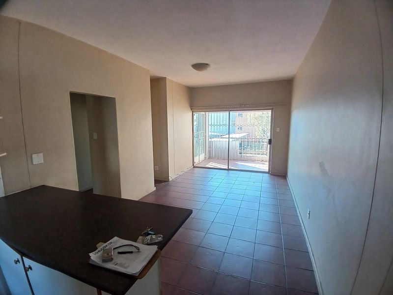 An open-plan living area featuring tiled flooring and a sliding glass door leading to a balcony, providing access to natural light.