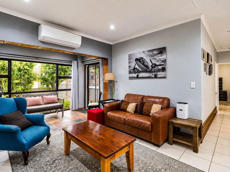 A well-maintained living room featuring tiled flooring, recessed lighting, and a split-system air conditioner, with direct access to an outdoor area through sliding doors.