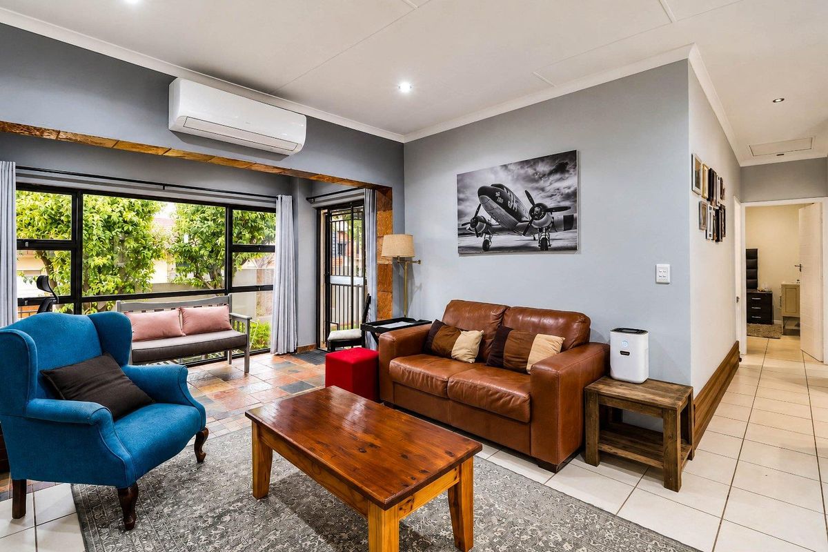 A well-maintained living room featuring tiled flooring, recessed lighting, and a split-system air conditioner, with direct access to an outdoor area through sliding doors.