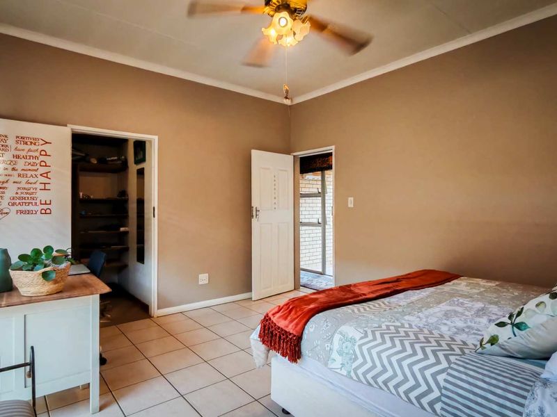 A bedroom featuring tiled flooring, a ceiling fan, and an adjoining walk-in closet or storage area.