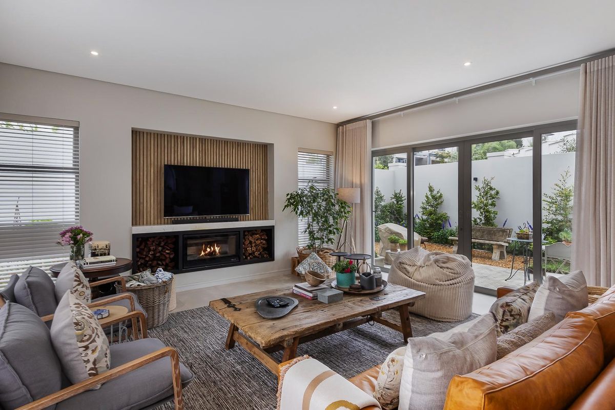 A modern living room featuring a built-in fireplace with timber slat feature wall, recessed shelving, and large sliding glass doors opening to a private patio.