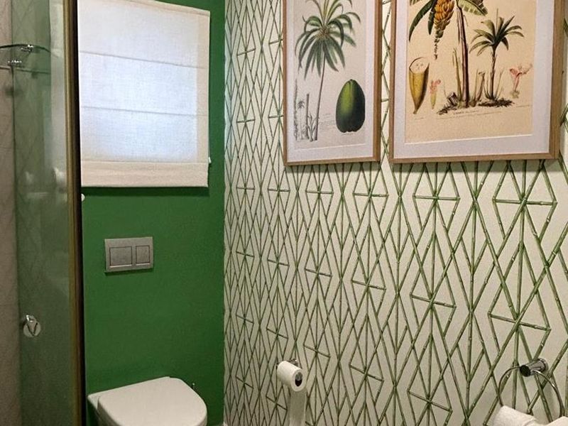 A modern bathroom featuring a wall-mounted toilet with a concealed cistern, a glass shower enclosure, and a wall-mounted basin with decorative wallpaper.