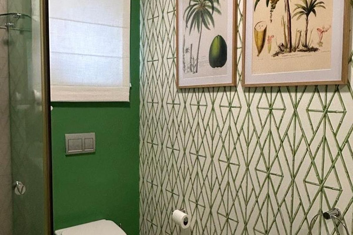 A modern bathroom featuring a wall-mounted toilet with a concealed cistern, a glass shower enclosure, and a wall-mounted basin with decorative wallpaper.