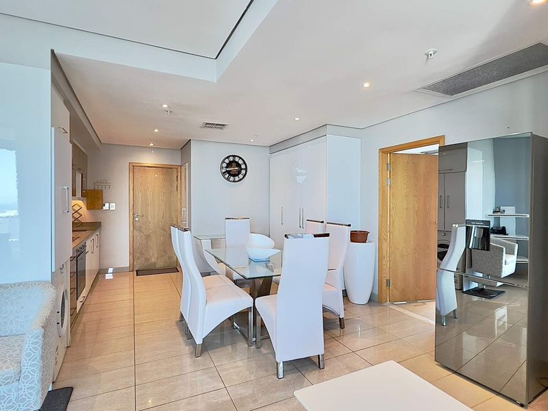 Modern open-plan living and dining area featuring sleek tiled flooring, recessed lighting, and integrated kitchen cabinetry with built-in appliances.
