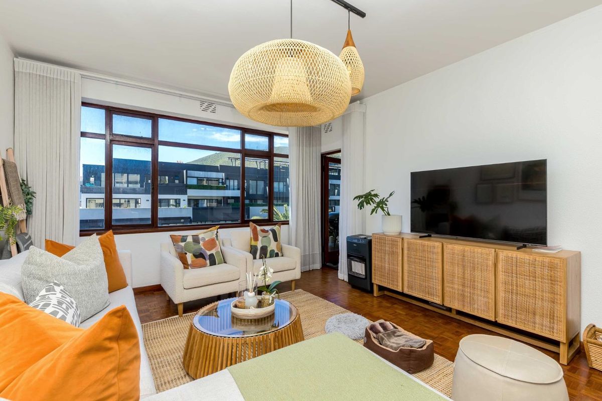 A bright and well-maintained living room featuring warm parquet flooring and a large window that provides ample natural light.