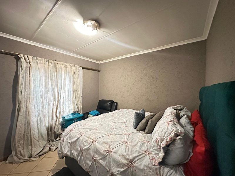 A bedroom featuring tiled flooring and a ceiling light fixture, requiring some cosmetic updates to the ceiling and wall finishes.