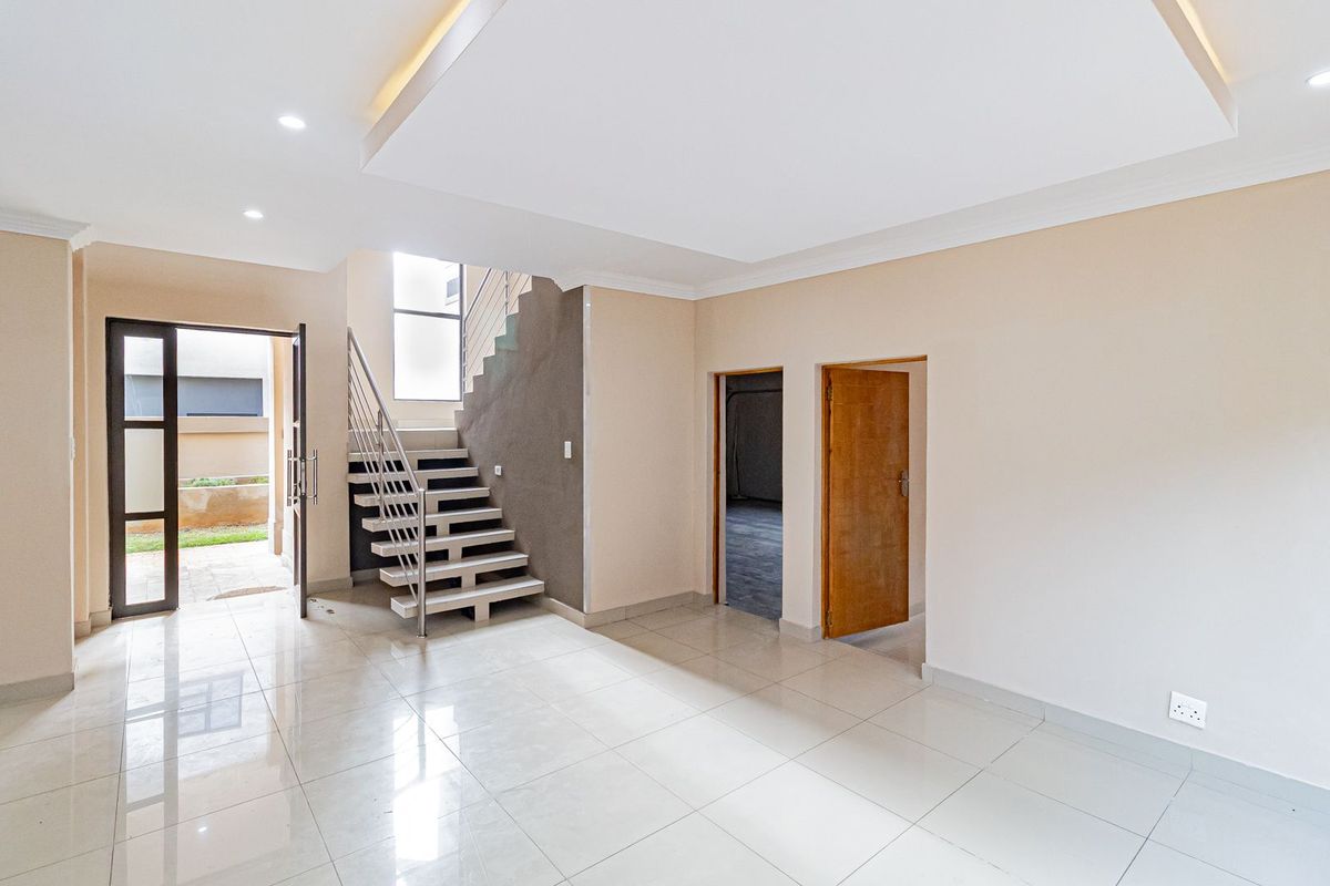 Spacious open-plan living area featuring modern tiled flooring, a contemporary staircase, recessed ceiling lighting, and direct access to the exterior.