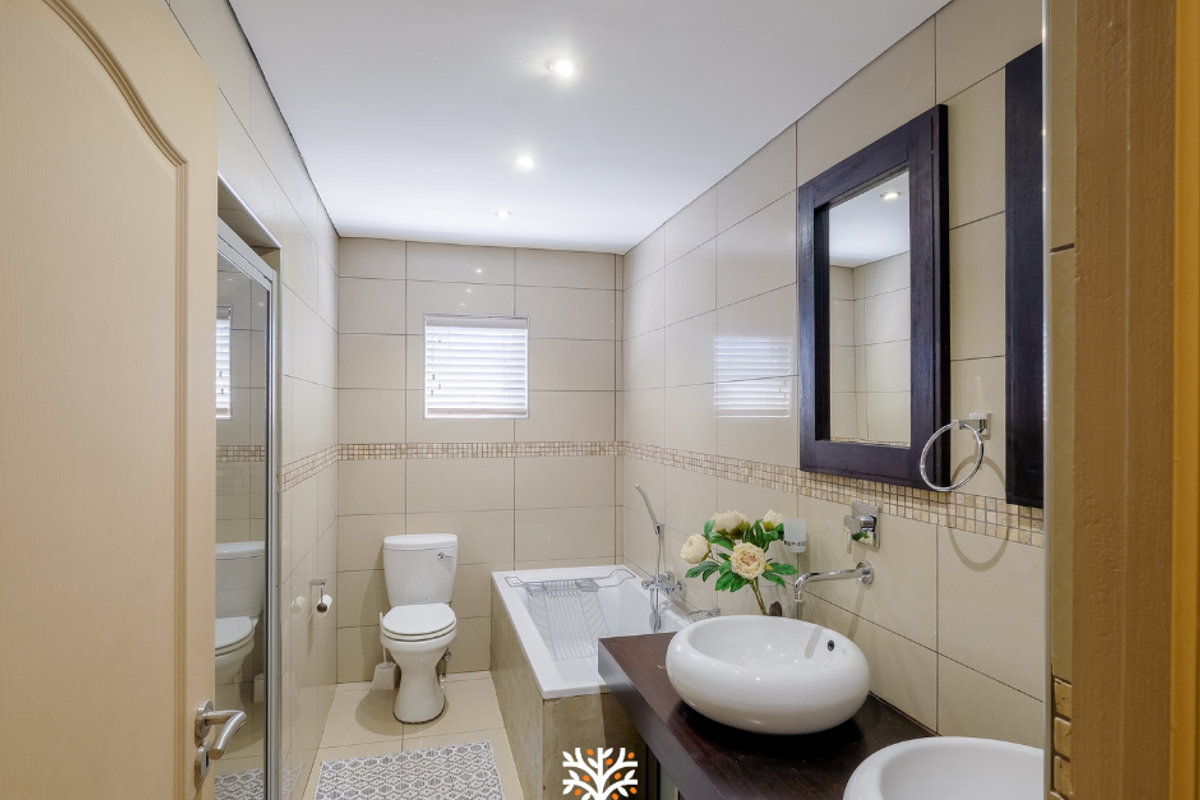 A well-maintained bathroom featuring a double vanity with vessel sinks, a bathtub, and neutral wall tiling.