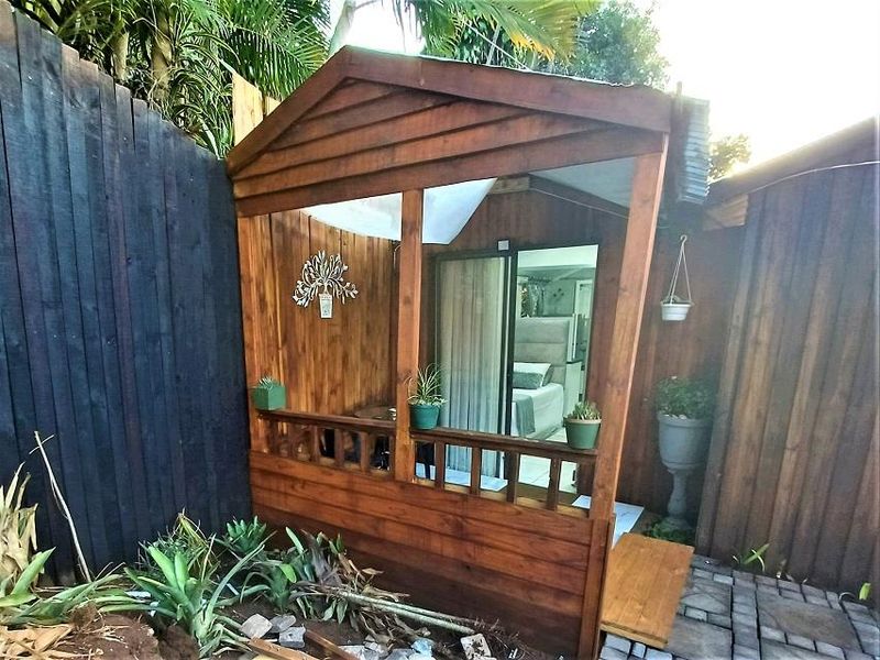 A charming timber-clad patio area featuring a wooden balustrade and sliding glass door access to the interior living space.