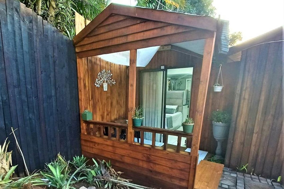 A charming timber-clad patio area featuring a wooden balustrade and sliding glass door access to the interior living space.