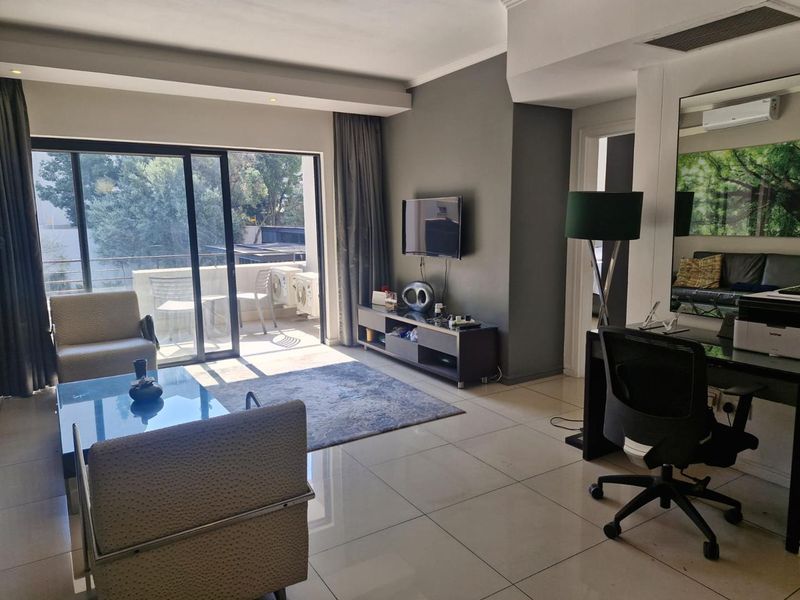 A bright living room featuring large sliding glass doors leading to a balcony, tiled flooring, and neutral wall finishes.