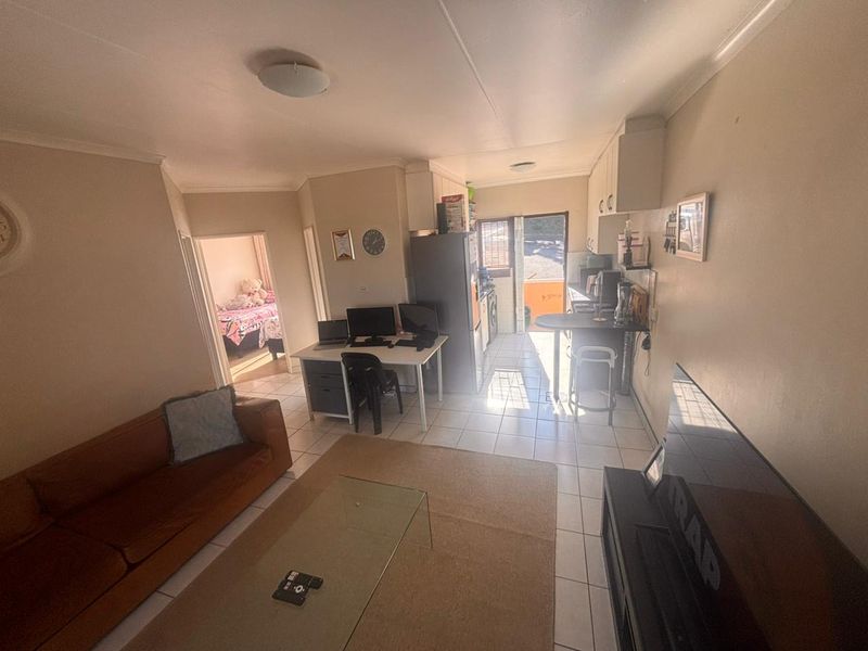 Open-plan living and kitchen area featuring tiled flooring, built-in cabinetry, and a breakfast bar, with direct access to an outdoor space.