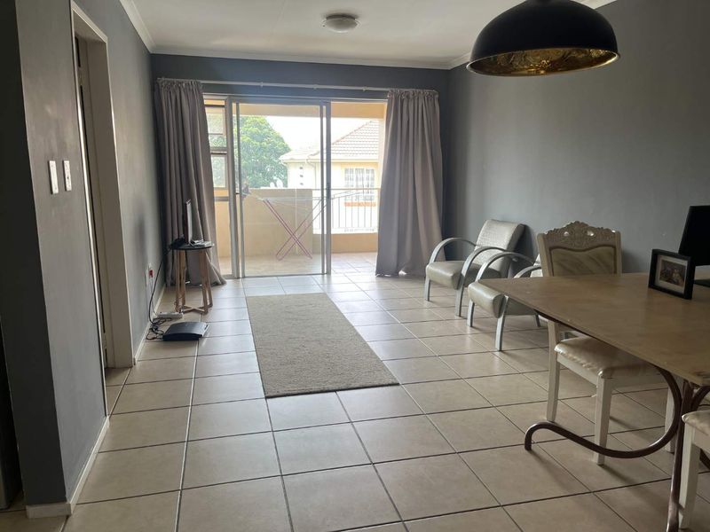 Spacious living area featuring neutral tiled flooring and a large sliding glass door providing access to the balcony.