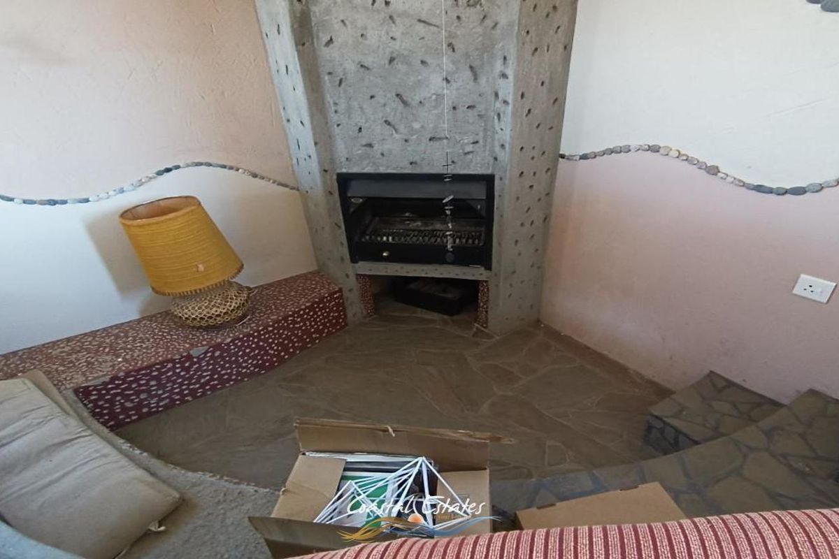 A living room area featuring a unique built-in concrete fireplace with a stone hearth and flagstone flooring.