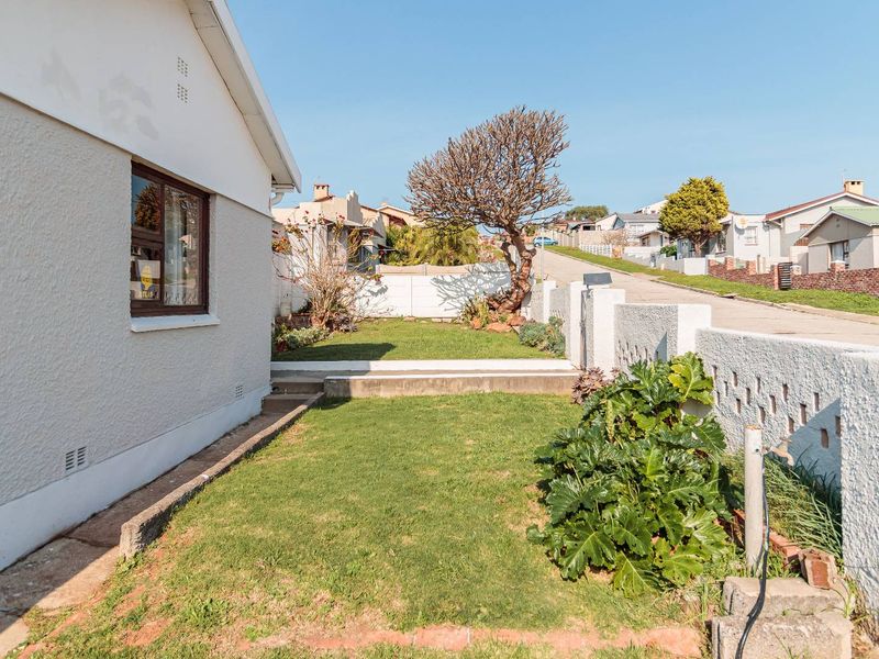 Front exterior view of the property featuring a small lawn, boundary wall, and concrete driveway access from the street.