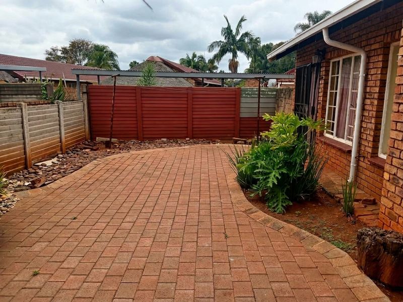 A private rear courtyard featuring brick paving, face brick exterior walls, and a combination of precast concrete and timber boundary fencing.