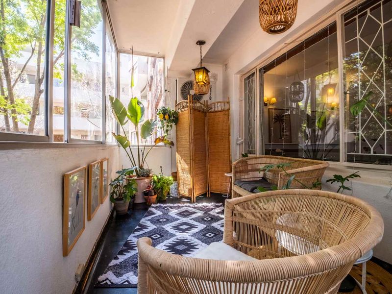 A bright, enclosed balcony featuring large sliding windows, security bars, and integrated lighting, offering a versatile space for relaxation.