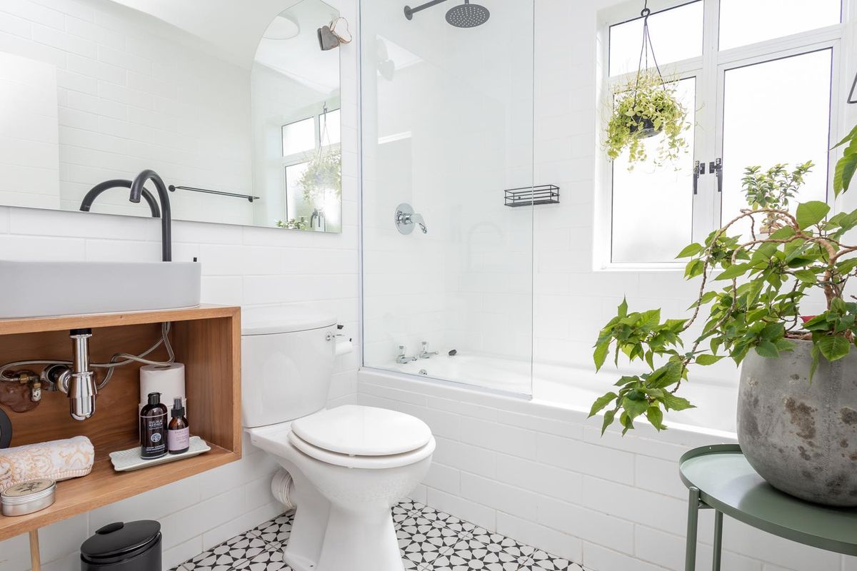 Modern bathroom featuring a floating vanity with vessel sink, subway tiled walls, patterned floor tiles, and a combined bathtub and shower with glass screen.