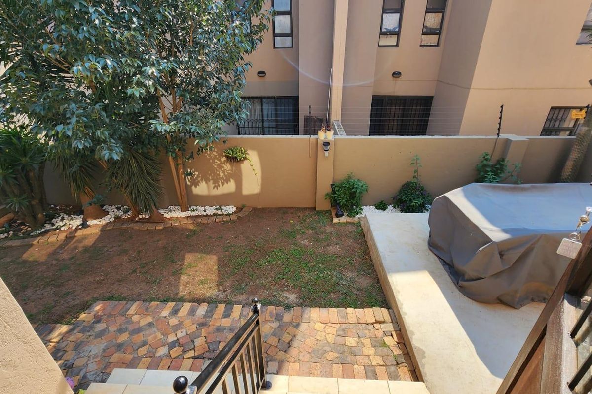 A private rear garden featuring a brick-paved area, a concrete patio, and a secure boundary wall with electric fencing.