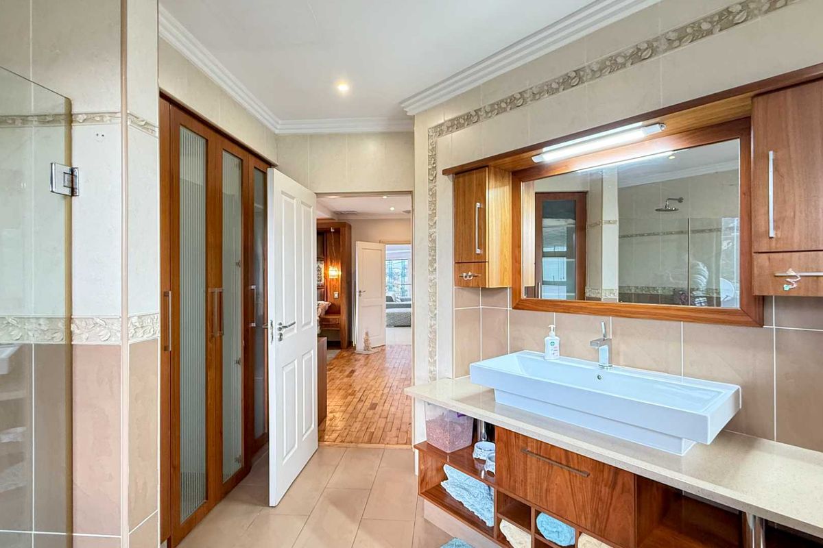 A well-maintained bathroom featuring a modern vessel sink, wooden vanity cabinetry, integrated mirror, and tiled wall finishes.