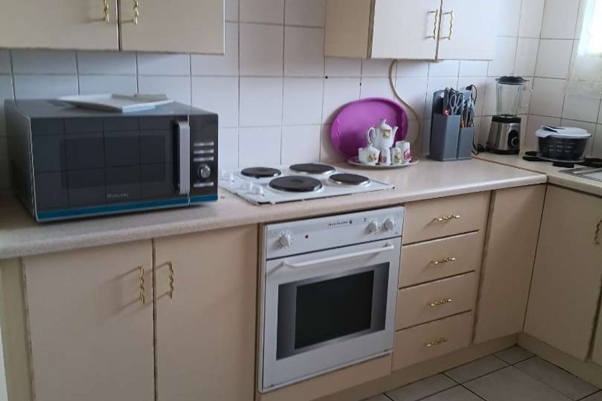 A functional kitchen featuring built-in cabinetry, laminate countertops, an electric hob, and an integrated oven with tiled backsplash and flooring.