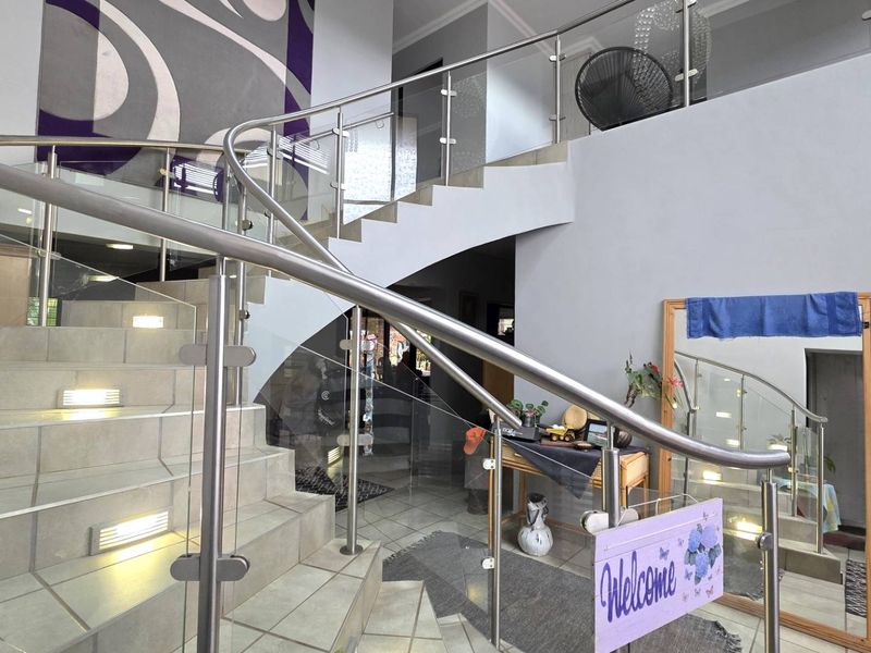 Spacious entrance hall featuring a modern tiled staircase with stainless steel and glass balustrades and integrated stair lighting.