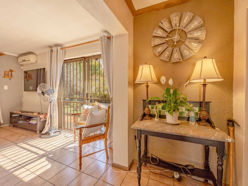 A living area featuring tiled flooring, a wall-mounted air conditioning unit, and a sliding door with security gate leading to the exterior.