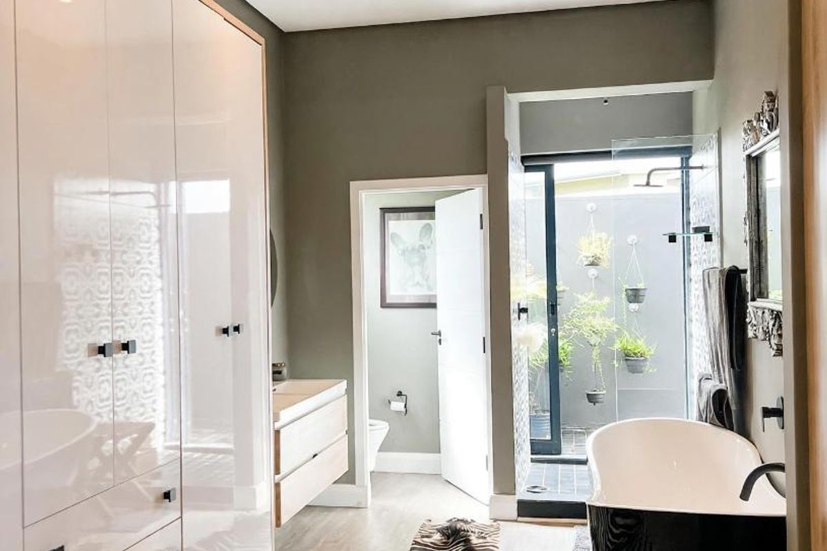 Modern bathroom featuring a sleek freestanding bathtub, extensive built-in cabinetry, a vanity, and a private walk-in shower area with access to a small courtyard.
