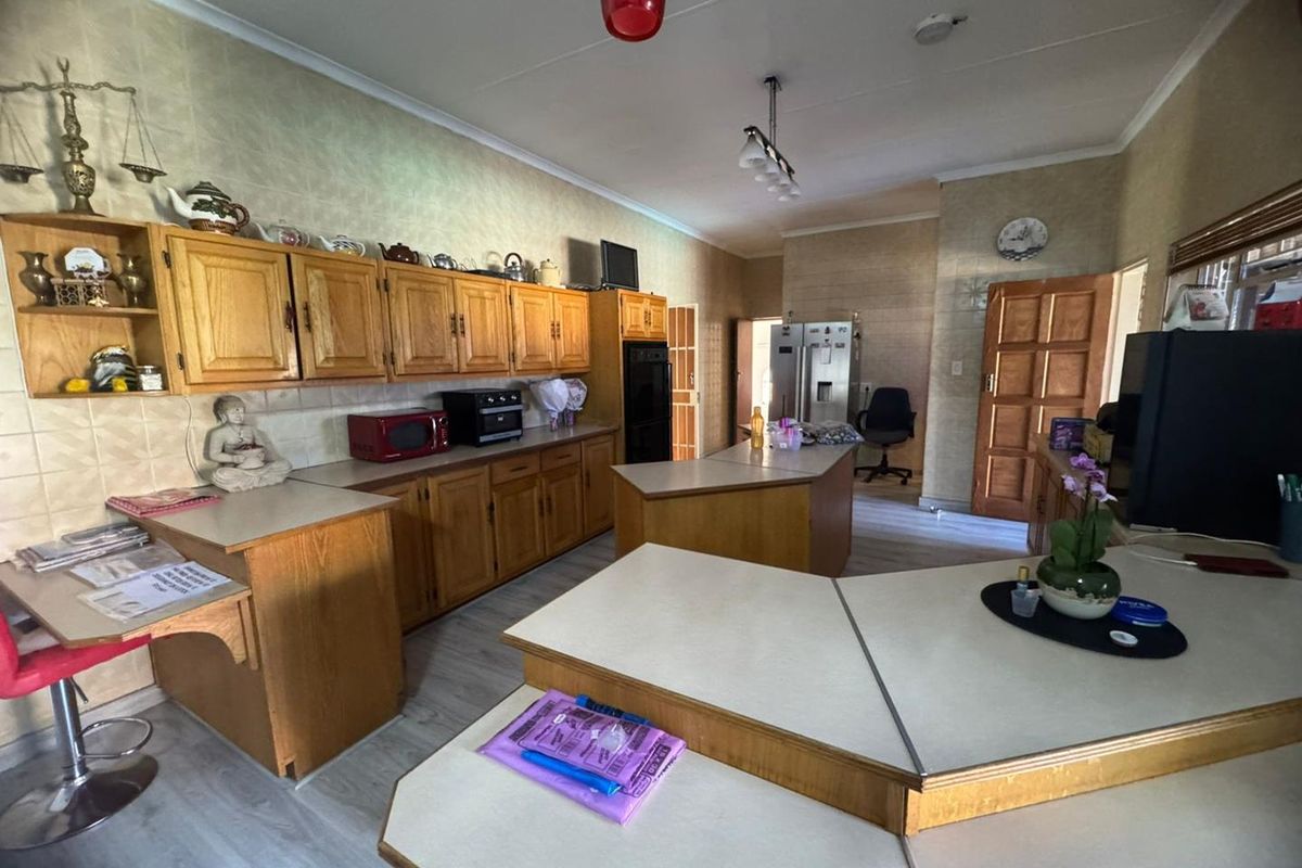 A spacious kitchen featuring extensive wooden cabinetry, laminate countertops, and a central island, offering a functional layout with ample storage and workspace.