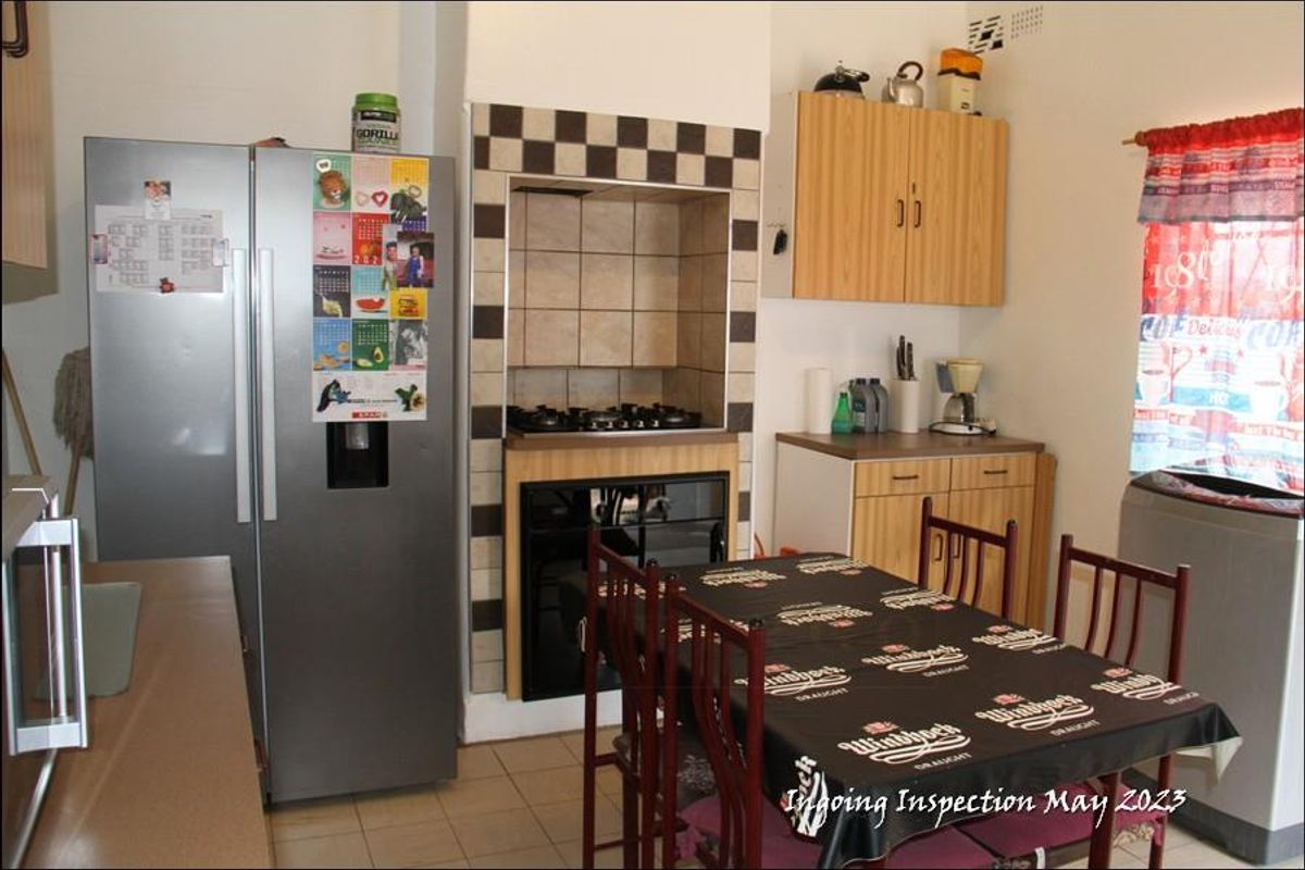 A functional kitchen featuring built-in cabinetry, a tiled hob alcove, and tiled flooring, providing a practical space for meal preparation.
