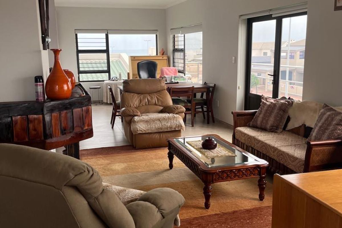 Spacious living area featuring tiled flooring, large windows, and sliding glass doors that provide natural light and access to the exterior.