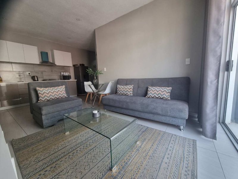 An open-plan living area featuring tiled floors, a modern kitchen with built-in cabinetry, and a sliding glass door leading to an outdoor space.