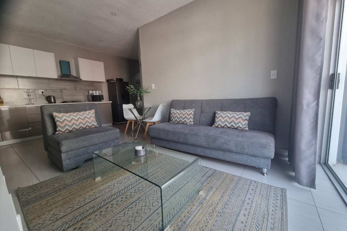 An open-plan living area featuring tiled floors, a modern kitchen with built-in cabinetry, and a sliding glass door leading to an outdoor space.