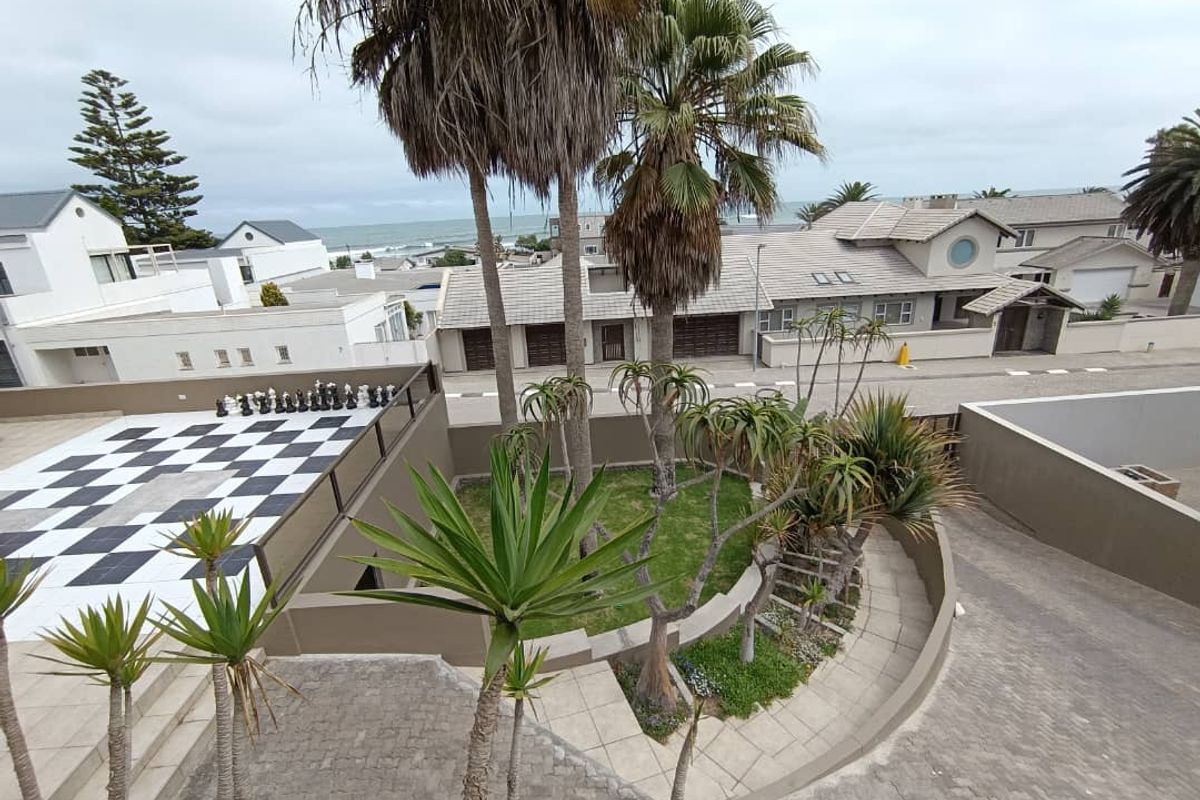 Elevated view of a landscaped garden area featuring paved pathways, mature palm trees, and a unique checkered patio space.