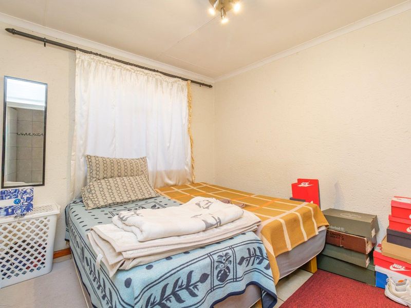 A compact bedroom featuring a standard layout with a curtain rod and ceiling cornice, requiring cosmetic updates to the walls and ceiling.