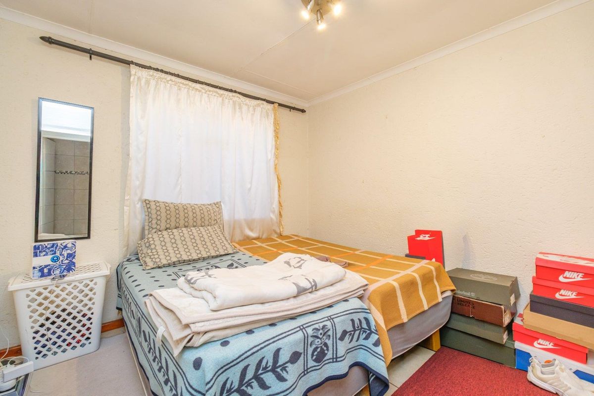 A compact bedroom featuring a standard layout with a curtain rod and ceiling cornice, requiring cosmetic updates to the walls and ceiling.